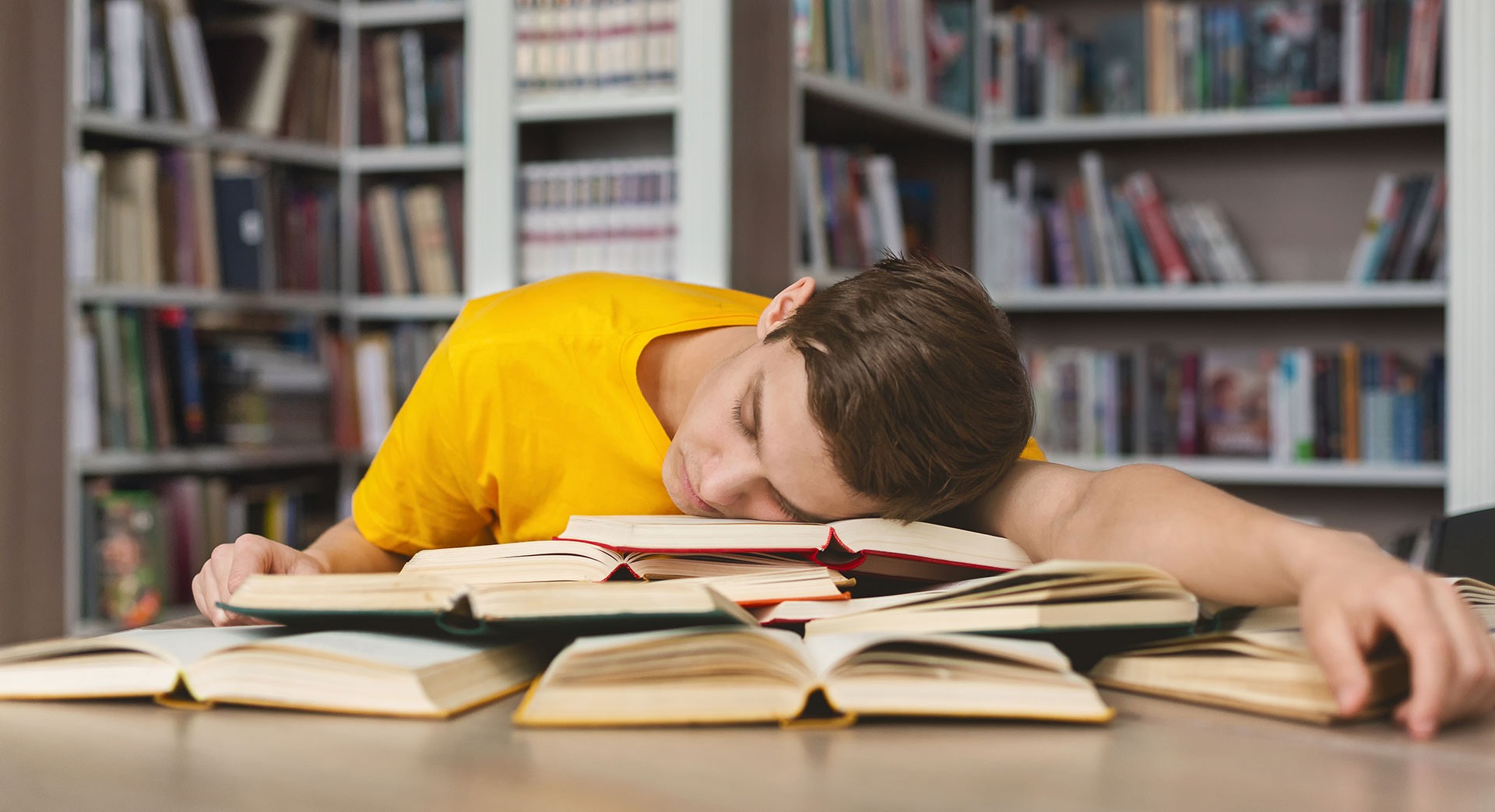 Un homme endormi sur une pile de livres